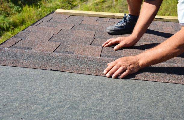 contractor installing new roof shingles by hand